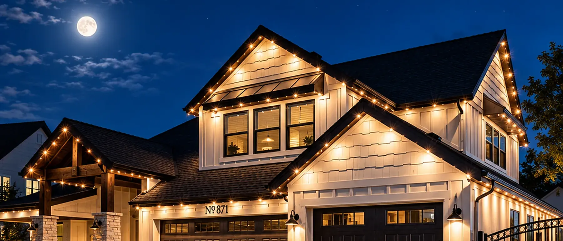 Warm white LivSmart lighting washing a board-and-batten gable and garage elevation after dark